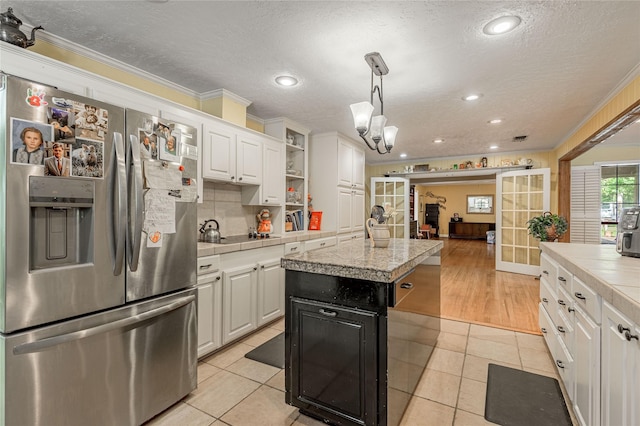 459 Brookwood Dr, Diboll, TX 75941 - kitchen with stainless steel fridge, crown molding, white cabinets, light tile patterned flooring, and a textured ceiling