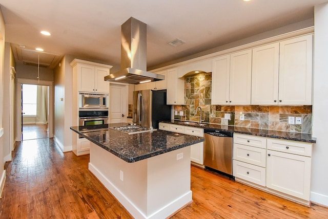 5238 Nett St, Houston, TX 77007 - kitchen featuring appliances with stainless steel finishes, island range hood, recessed lighting, white cabinets, and decorative backsplash