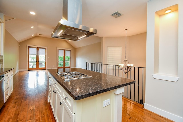 5238 Nett St, Houston, TX 77007 - kitchen featuring range hood, gas cooktop, a chandelier, light wood-style floors, and white cabinetry