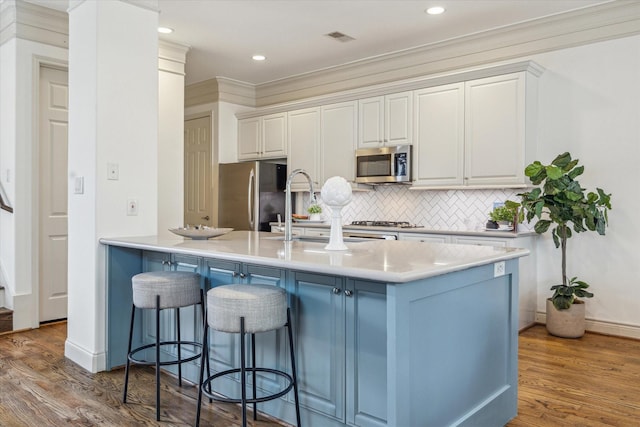 1518 Dunlavy St, Houston, TX 77006 - kitchen featuring stainless steel appliances, a breakfast bar, wood finished floors, tasteful backsplash, and light countertops