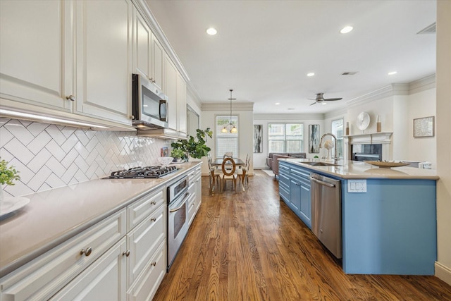 1518 Dunlavy St, Houston, TX 77006 - kitchen featuring appliances with stainless steel finishes, blue cabinets, ornamental molding, decorative backsplash, and dark wood-style floors