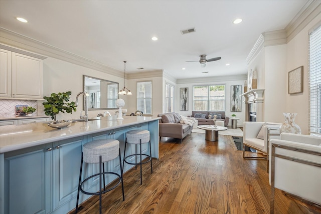 1518 Dunlavy St, Houston, TX 77006 - kitchen with a kitchen breakfast bar, light countertops, ornamental molding, dark wood-style flooring, and open floor plan