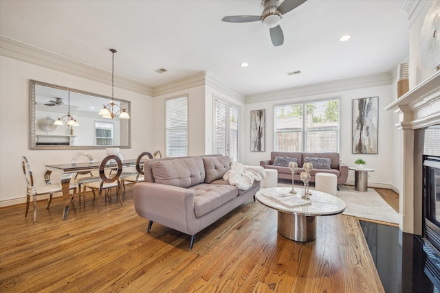 1518 Dunlavy St, Houston, TX 77006 - living room featuring wood finished floors, crown molding, a ceiling fan, a glass covered fireplace, and a chandelier