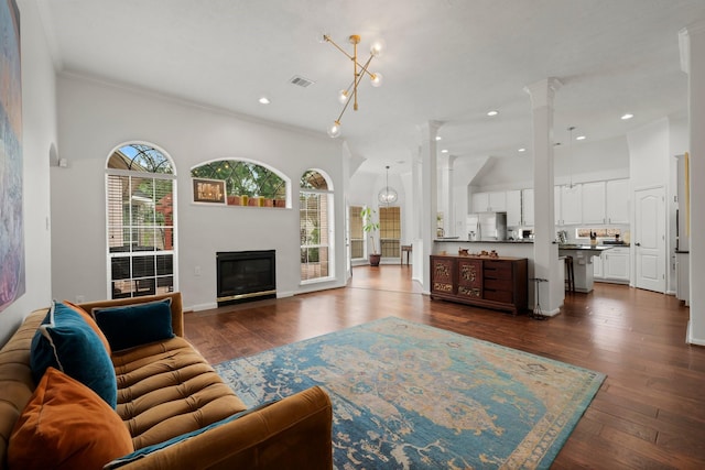 6531 Glenhill Dr, Spring, TX 77389 - living room featuring crown molding, dark wood finished floors, a glass covered fireplace, recessed lighting, and decorative columns