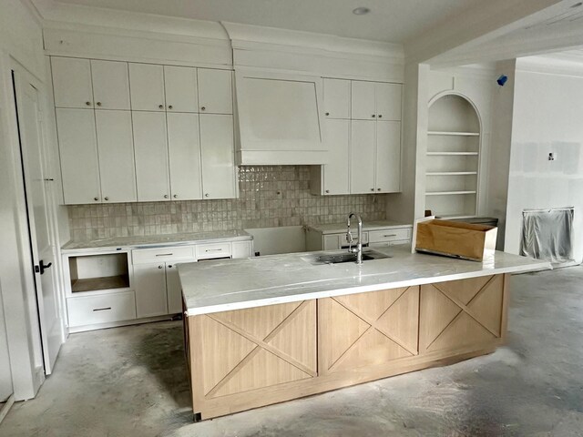 2434 Quenby St, Houston, TX 77005 - kitchen featuring concrete flooring, tasteful backsplash, white cabinetry, a kitchen island with sink, and ornamental molding