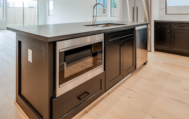 2434 Quenby St, Houston, TX 77005 - kitchen featuring stainless steel appliances, light wood-style floors, a center island with sink, and healthy amount of natural light
