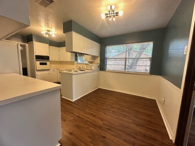 1215 Briar Ln, Wharton, TX 77488 - kitchen with oven, a textured ceiling, a chandelier, dark wood-style flooring, and fridge
