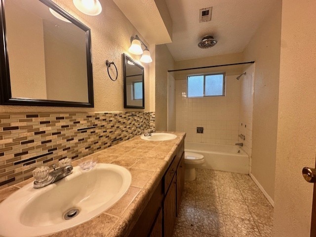 1215 Briar Ln, Wharton, TX 77488 - full bathroom with double vanity, shower / washtub combination, a textured wall, and tile walls