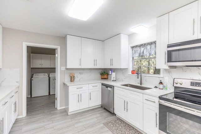 804 Camphor Cir, Village Mills, TX 77663 - kitchen featuring appliances with stainless steel finishes, separate washer and dryer, light countertops, and white cabinets