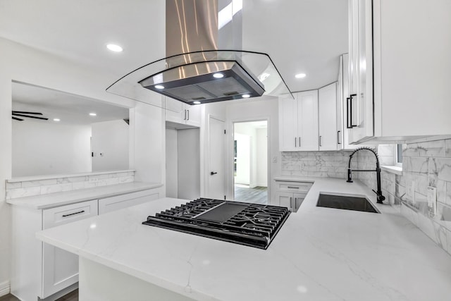9602 Ballin David Dr, Spring, TX 77379 - kitchen with island range hood, black gas stovetop, light stone countertops, a peninsula, and backsplash