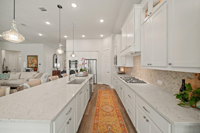 13305 Newcastle Creek Ct, Houston, TX 77059 - kitchen featuring stainless steel appliances, wood finished floors, open floor plan, white cabinetry, and recessed lighting