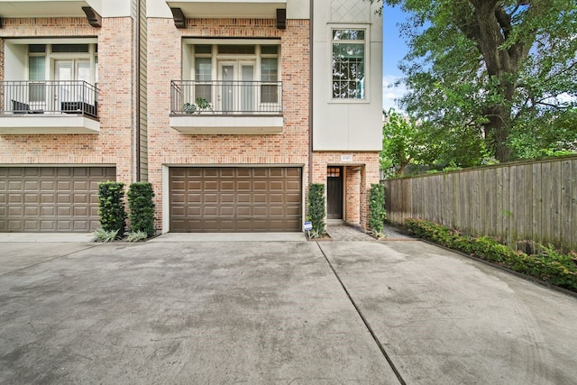 1034 W 26th St Unit D, Houston, TX 77008 - view of property featuring driveway, a garage, brick siding, and a balcony