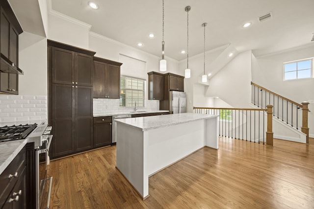 1034 W 26th St Unit D, Houston, TX 77008 - kitchen featuring stainless steel appliances, a center island, dark brown cabinets, recessed lighting, and wood finished floors