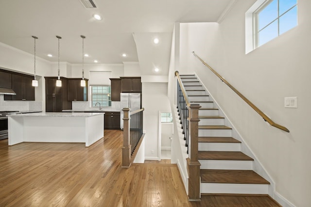 1034 W 26th St Unit D, Houston, TX 77008 - kitchen featuring stainless steel appliances, dark brown cabinetry, tasteful backsplash, a center island, and ornamental molding
