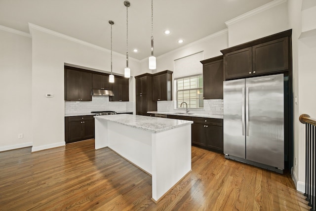 1034 W 26th St Unit D, Houston, TX 77008 - kitchen with freestanding refrigerator, under cabinet range hood, dark brown cabinetry, a kitchen island, and ornamental molding
