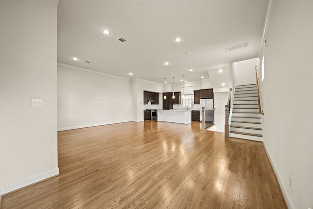1034 W 26th St Unit D, Houston, TX 77008 - unfurnished living room with recessed lighting, light wood-style flooring, ornamental molding, and stairs