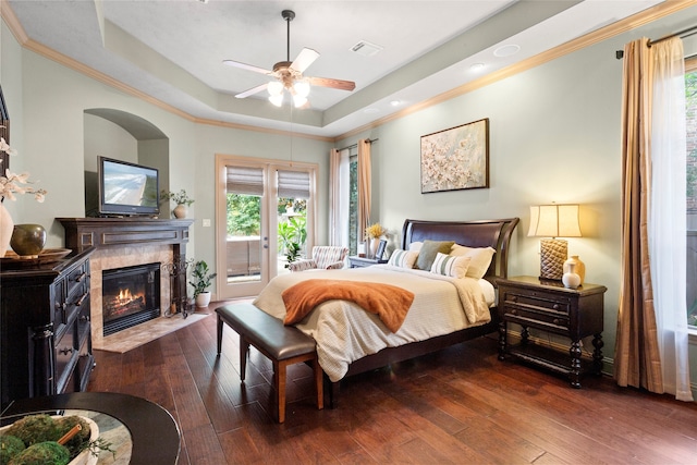 12902 Tamarack Bend Ln, Humble, TX 77346 - bedroom with a raised ceiling, access to outside, dark wood finished floors, a fireplace, and multiple windows