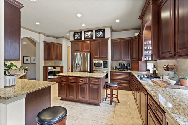 12902 Tamarack Bend Ln, Humble, TX 77346 - kitchen with stainless steel appliances, arched walkways, ornamental molding, tasteful backsplash, and a kitchen breakfast bar
