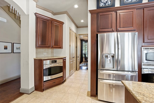 12902 Tamarack Bend Ln, Humble, TX 77346 - kitchen featuring appliances with stainless steel finishes, crown molding, light stone counters, tasteful backsplash, and arched walkways