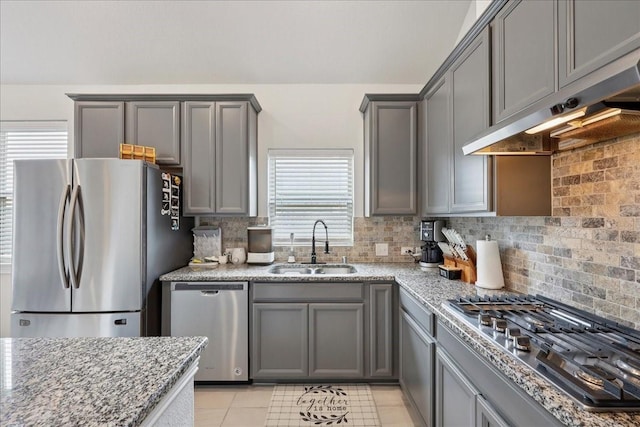 9111 Regan Way, Mont Belvieu, TX 77523 - kitchen with stainless steel appliances, gray cabinetry, under cabinet range hood, and decorative backsplash