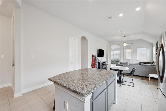 9111 Regan Way, Mont Belvieu, TX 77523 - kitchen featuring a ceiling fan, arched walkways, light tile patterned floors, a center island, and vaulted ceiling