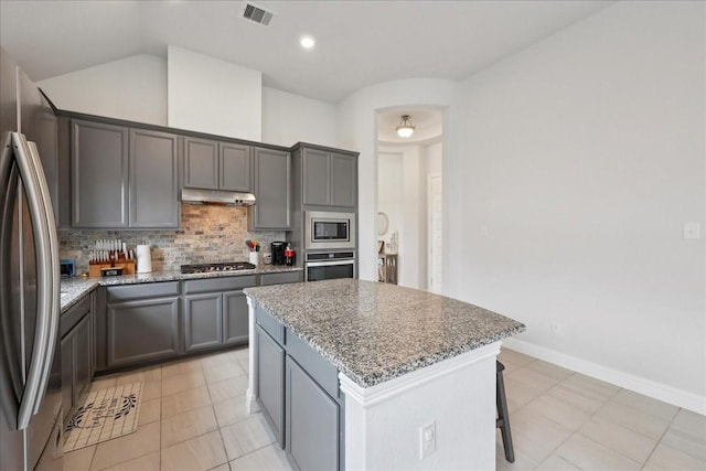 9111 Regan Way, Mont Belvieu, TX 77523 - kitchen featuring stainless steel appliances, under cabinet range hood, a kitchen island, light stone counters, and backsplash