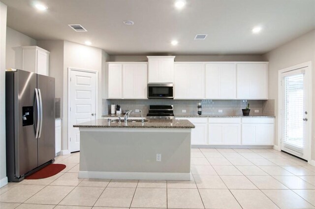 11215 Pavonia Creek Ct, Richmond, TX 77406 - kitchen with stainless steel appliances, decorative backsplash, dark stone counters, white cabinets, and an island with sink
