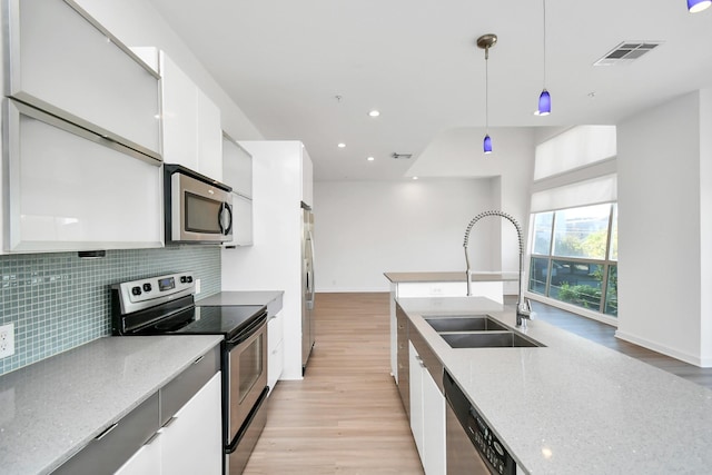 207 Pierce St Unit 301, Houston, TX 77002 - kitchen with stainless steel appliances, modern cabinets, light wood-style flooring, tasteful backsplash, and white cabinetry