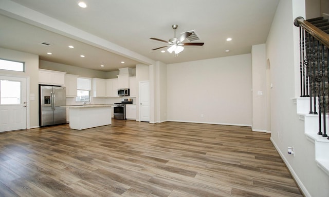 239 Biltmore Loop, Montgomery, TX 77316 - kitchen featuring appliances with stainless steel finishes, open floor plan, ceiling fan, white cabinetry, and a kitchen island
