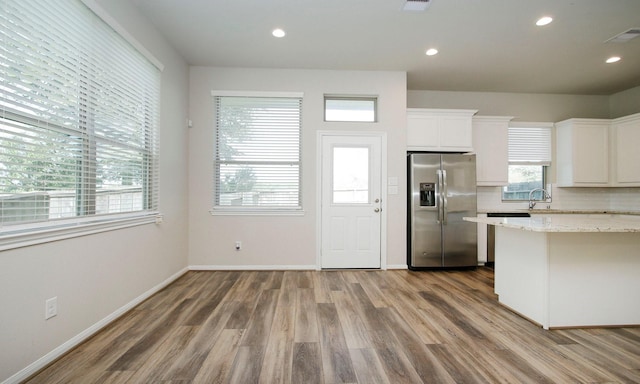 239 Biltmore Loop, Montgomery, TX 77316 - kitchen with stainless steel fridge with ice dispenser, wood finished floors, white cabinetry, light stone countertops, and decorative backsplash