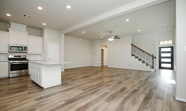 239 Biltmore Loop, Montgomery, TX 77316 - kitchen featuring stainless steel appliances, backsplash, light wood finished floors, white cabinetry, and open floor plan
