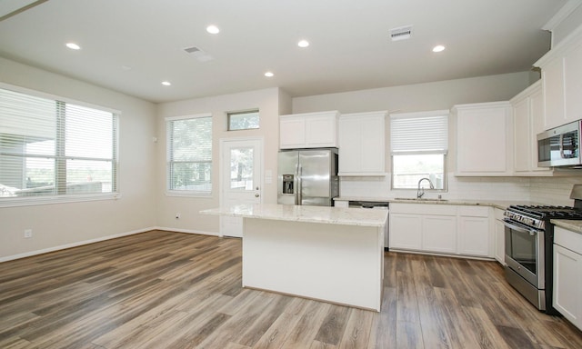 239 Biltmore Loop, Montgomery, TX 77316 - kitchen with appliances with stainless steel finishes, a kitchen island, backsplash, dark wood finished floors, and light stone counters