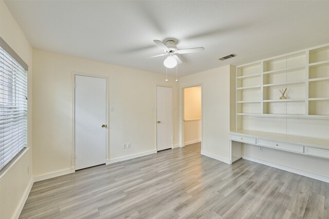 2308 Winrock Blvd Unit 173, Houston, TX 77057 - unfurnished bedroom featuring light wood finished floors, built in desk, and a ceiling fan