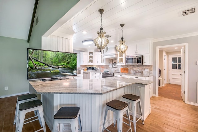 36602 Hondo Rd, Simonton, TX 77485 - kitchen featuring stainless steel appliances, white cabinetry, glass insert cabinets, a breakfast bar area, and a chandelier