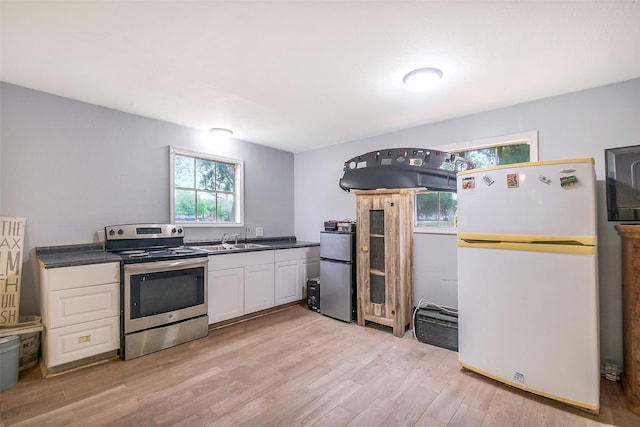 36602 Hondo Rd, Simonton, TX 77485 - kitchen featuring stainless steel appliances, light wood finished floors, white cabinets, and dark countertops