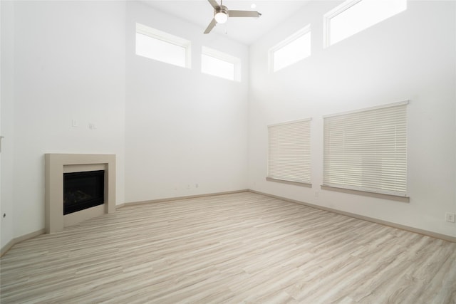 29423 Red Rocks Park Dr, Katy, TX 77494 - unfurnished living room featuring ceiling fan, wood finished floors, a fireplace, and a towering ceiling