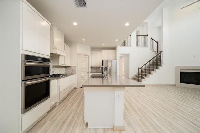29423 Red Rocks Park Dr, Katy, TX 77494 - kitchen featuring appliances with stainless steel finishes, light wood-style floors, backsplash, white cabinetry, and recessed lighting