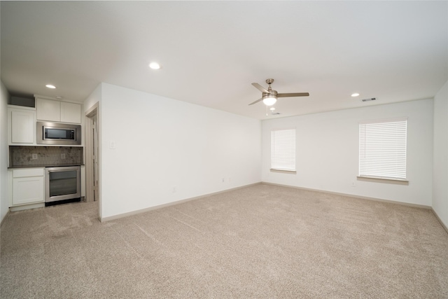 29423 Red Rocks Park Dr, Katy, TX 77494 - unfurnished living room with light colored carpet, recessed lighting, a ceiling fan, and beverage cooler