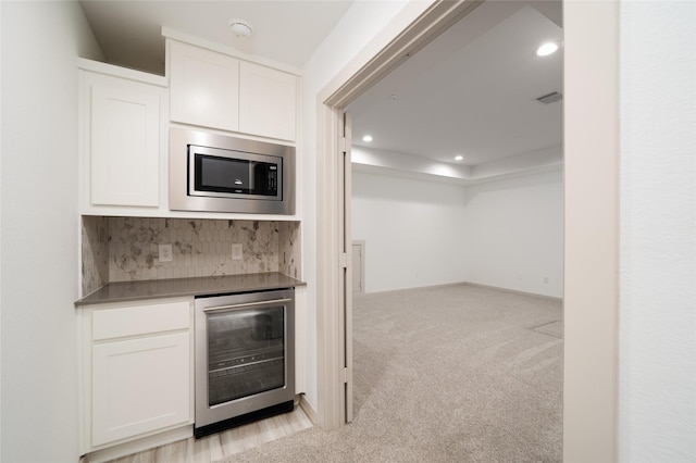 29423 Red Rocks Park Dr, Katy, TX 77494 - kitchen with beverage cooler, stainless steel microwave, light colored carpet, white cabinets, and recessed lighting