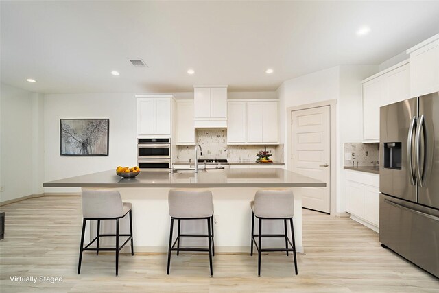 29423 Red Rocks Park Dr, Katy, TX 77494 - kitchen featuring appliances with stainless steel finishes, a kitchen bar, light wood-type flooring, and recessed lighting