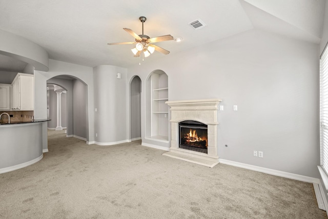 16115 Woodbend Trail Dr, Houston, TX 77070 - unfurnished living room with a ceiling fan, light colored carpet, a lit fireplace, arched walkways, and healthy amount of natural light