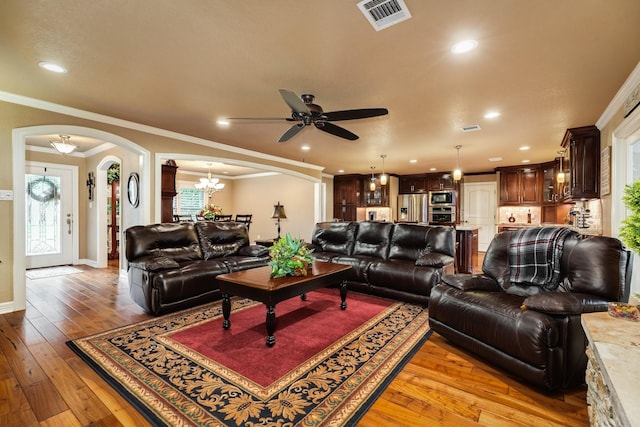 116 Cardinal St, Lake Jackson, TX 77566 - living area featuring arched walkways, a ceiling fan, light wood finished floors, ornamental molding, and a chandelier
