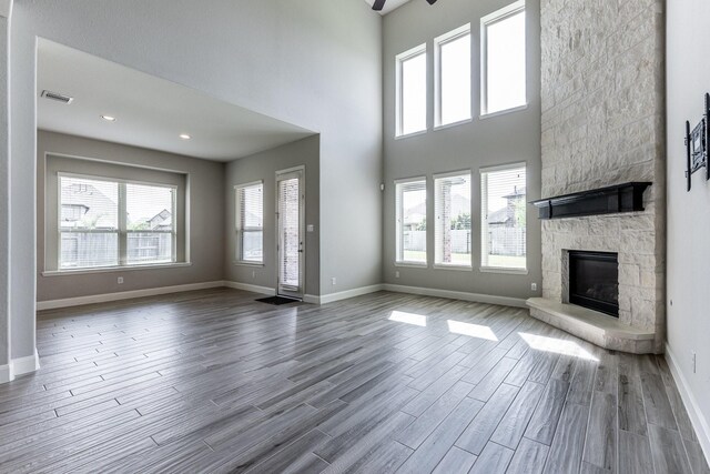 10318 Easterly Ln, Cypress, TX 77433 - unfurnished living room featuring a fireplace, healthy amount of natural light, wood finished floors, and a high ceiling