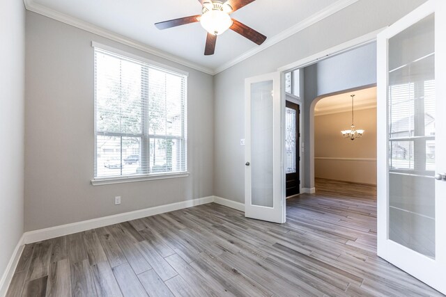10318 Easterly Ln, Cypress, TX 77433 - unfurnished room with crown molding, light wood-style flooring, a chandelier, ceiling fan, and arched walkways