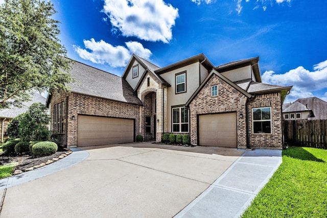 10318 Easterly Ln, Cypress, TX 77433 - french country style house featuring concrete driveway, stucco siding, an attached garage, brick siding, and roof with shingles