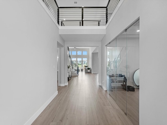 11319 Flying Admiral Dr, Cypress, TX 77433 - hallway with stairs, a towering ceiling, and light wood-style flooring