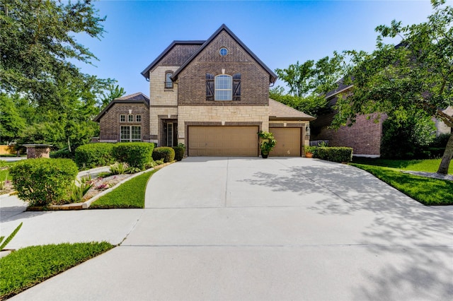 7003 Fall Creek Ln, Missouri City, TX 77459 - french country home with stone siding, concrete driveway, an attached garage, and brick siding