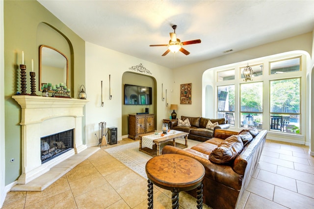 7003 Fall Creek Ln, Missouri City, TX 77459 - living room featuring arched walkways, ceiling fan, light tile patterned floors, and a fireplace with raised hearth