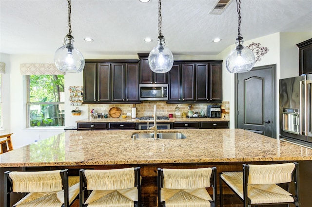 7003 Fall Creek Ln, Missouri City, TX 77459 - kitchen featuring stainless steel appliances, light stone counters, tasteful backsplash, decorative light fixtures, and recessed lighting