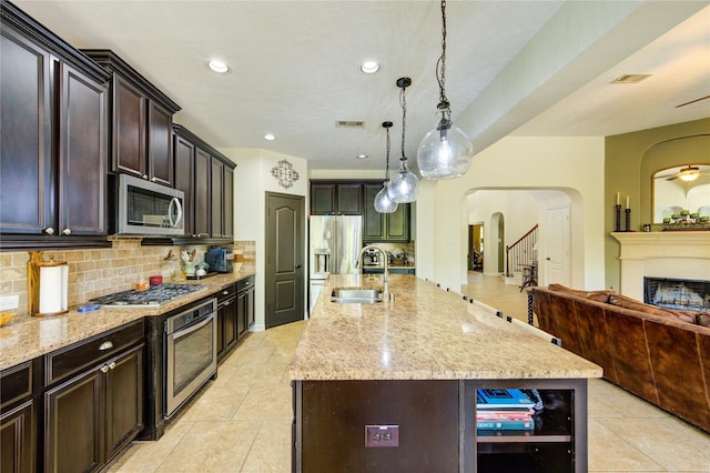 7003 Fall Creek Ln, Missouri City, TX 77459 - kitchen with stainless steel appliances, arched walkways, light stone countertops, backsplash, and open floor plan